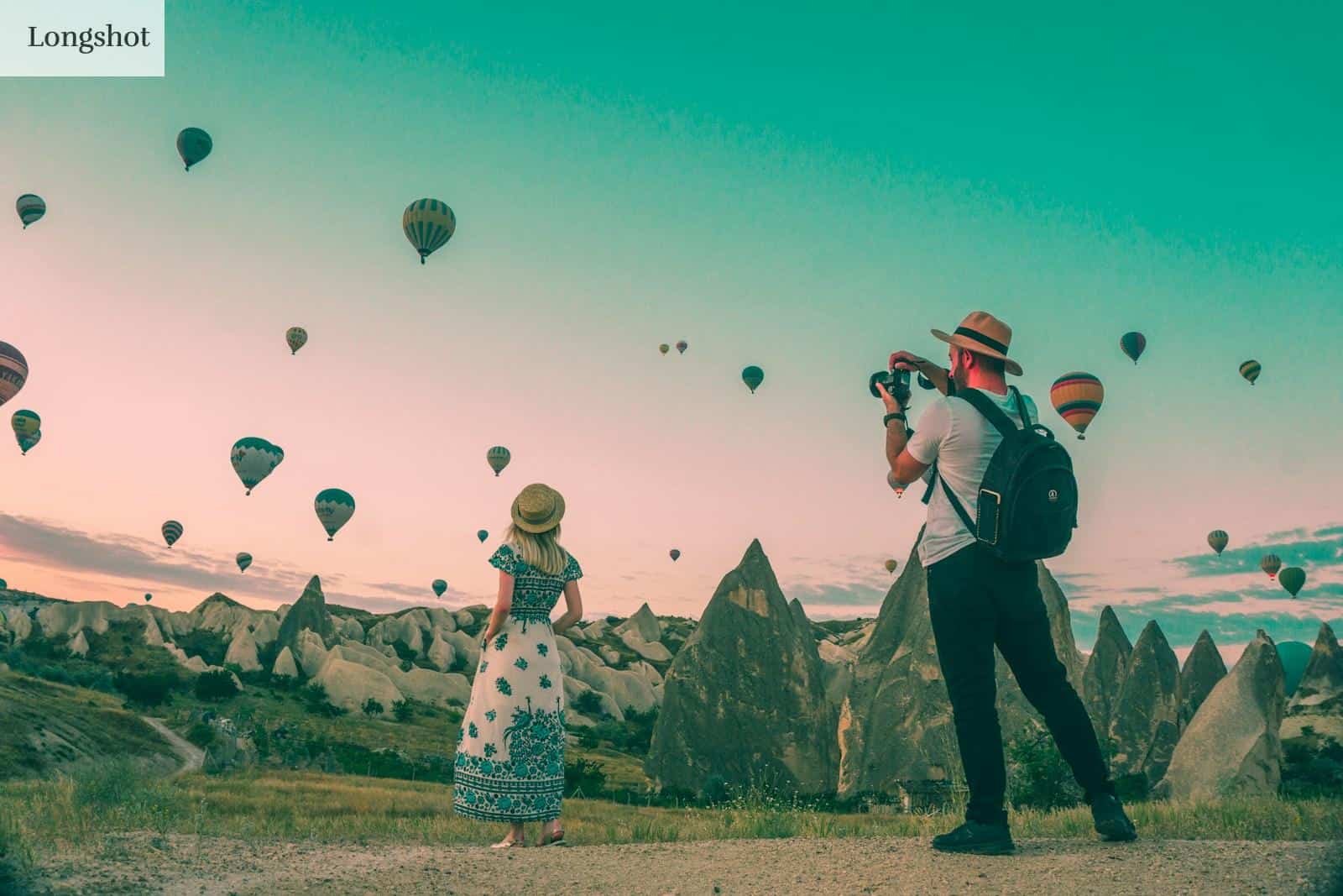 man taking photo of hot air balloons