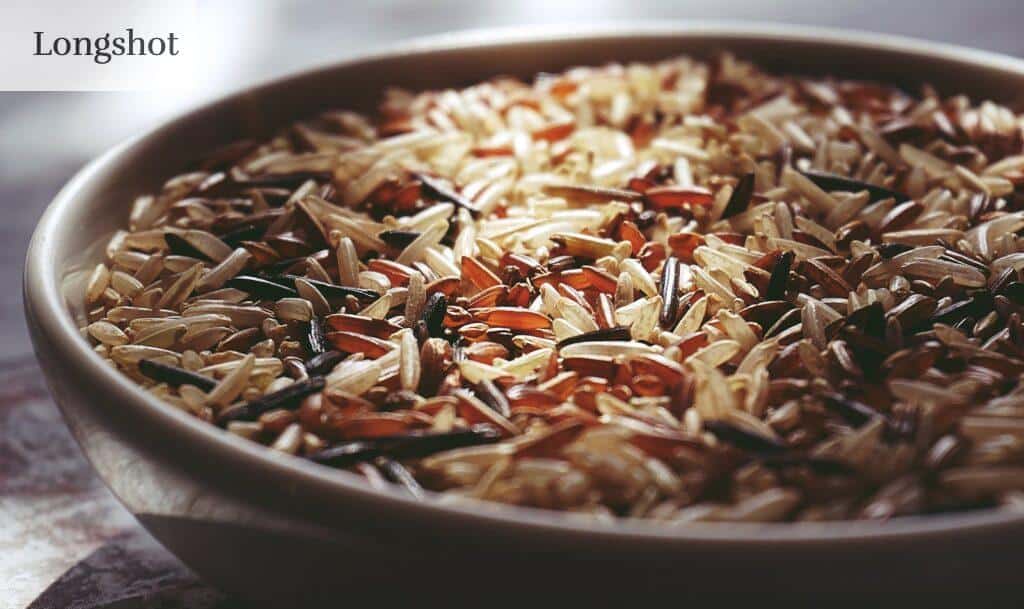 Macro shot of a ceramic bowl filled with colorful mixed wild rice, highlighting textures.