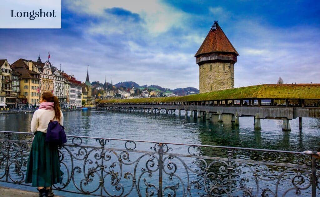 Traveler admires Chapel Bridge and Water Tower in Lucerne, Switzerland.