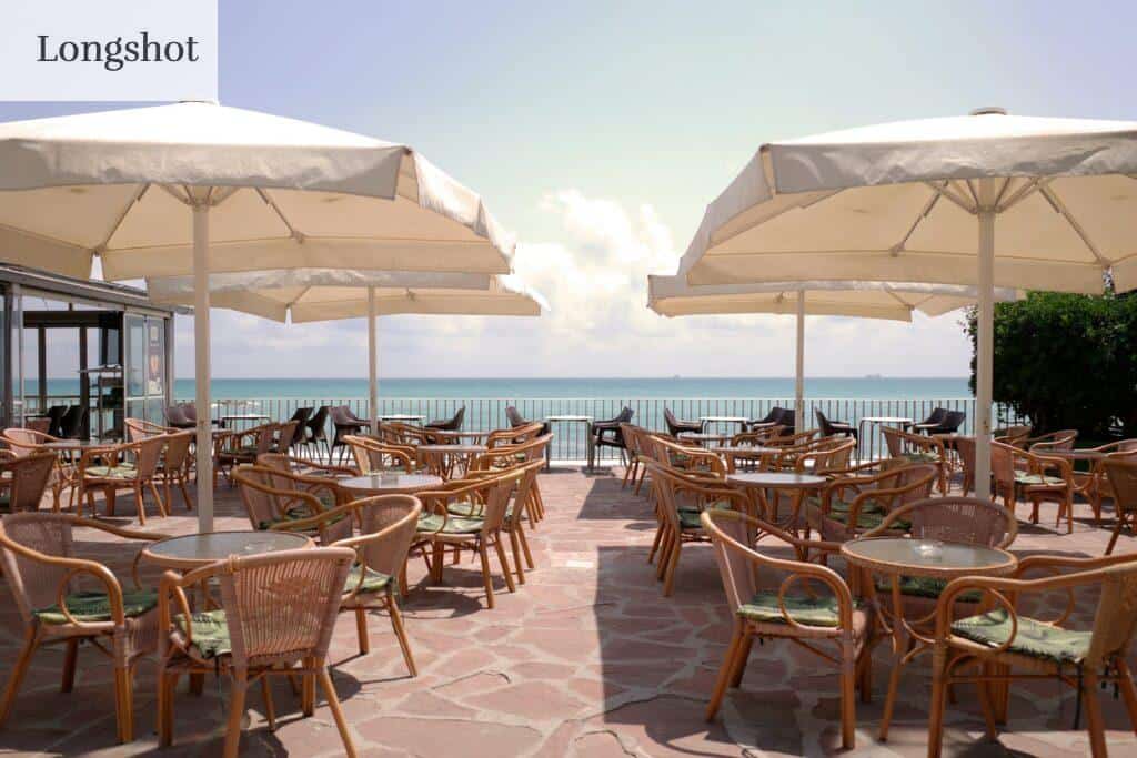 A bunch of tables and chairs with umbrellas