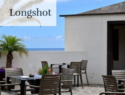 a patio with a table and chairs and a view of the ocean