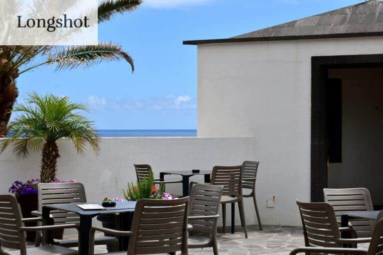 a patio with a table and chairs and a view of the ocean