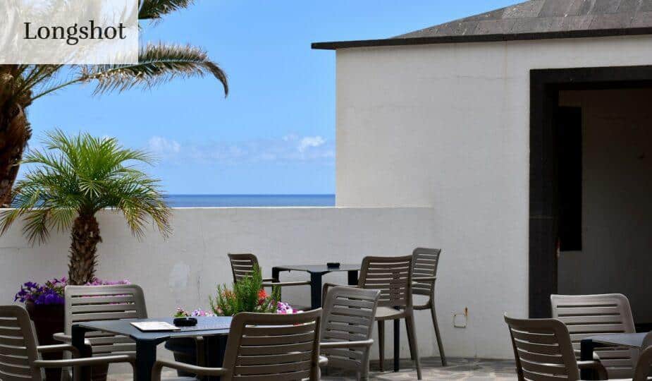 a patio with a table and chairs and a view of the ocean