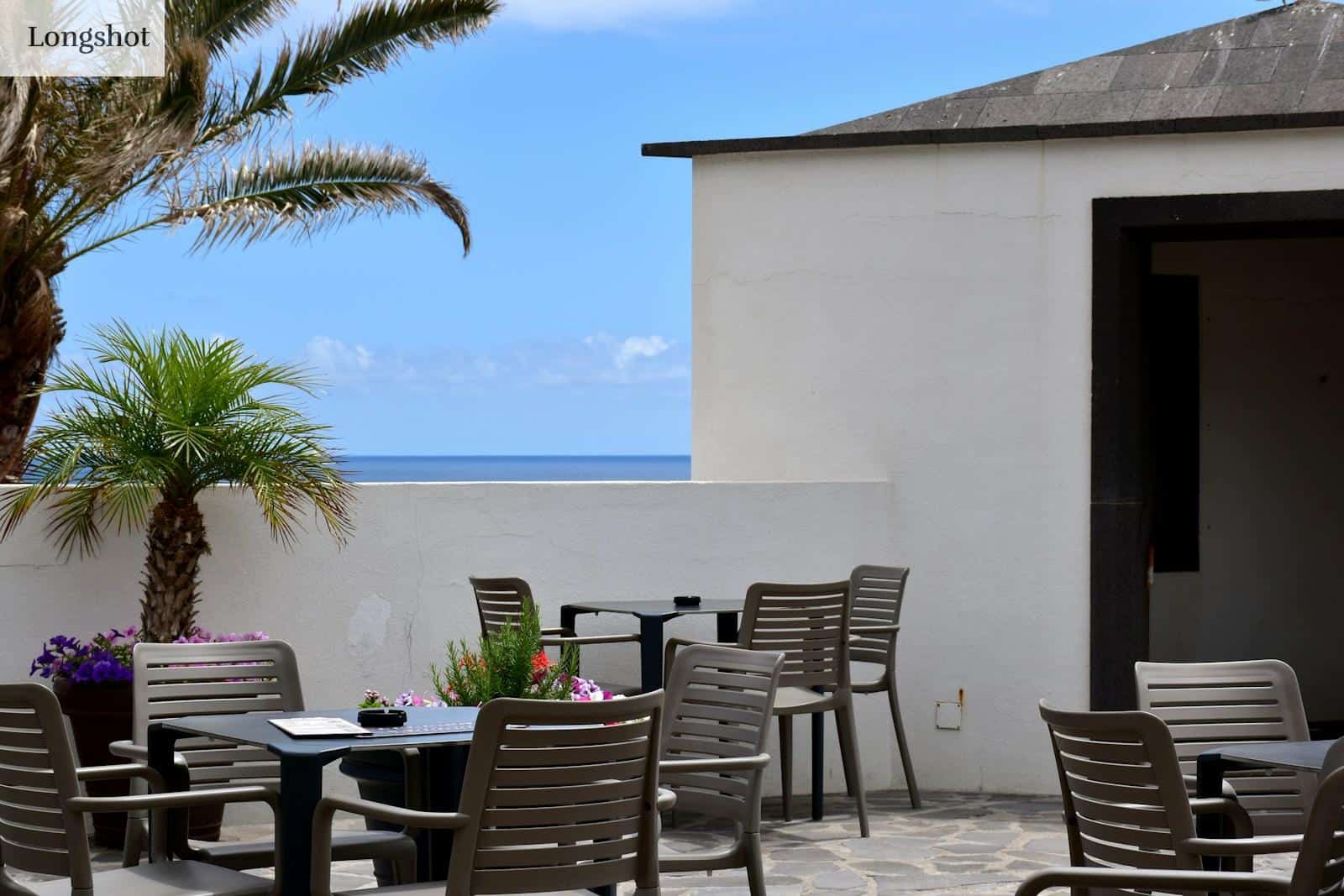 a patio with a table and chairs and a view of the ocean