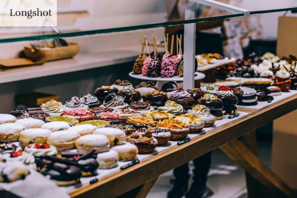 A tempting display of various donuts and pastries in a bakery. Ideal for food lovers and culinary enthusiasts.