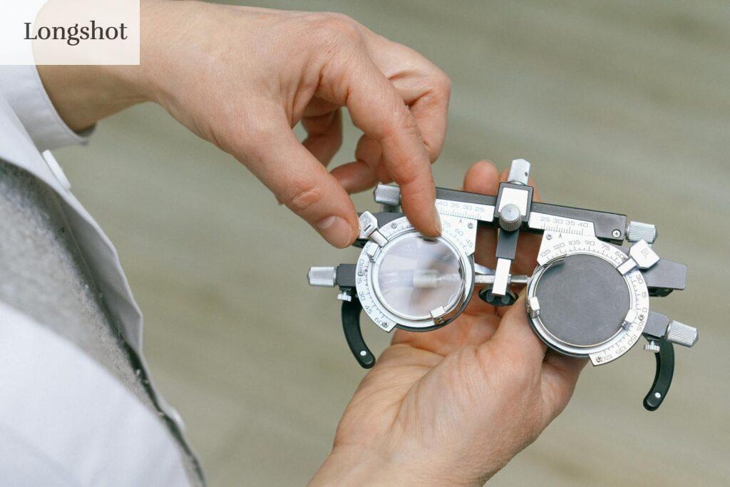 Crop unrecognizable medic in white coat taking measuring vision glasses while adjusting scale according to numerals written on metal surface